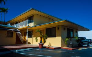 una casa amarilla con una palmera en un aparcamiento en King Motel - Miami, en Miami