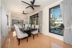 a dining room with a black table and white chairs at Rawai Escape 5BR Pool Villa Close to Everything in Ban Saiyuan (1)