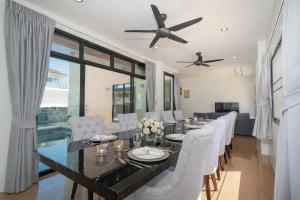 a dining room with a table and white chairs at Rawai Escape 5BR Pool Villa Close to Everything in Ban Saiyuan (1)
