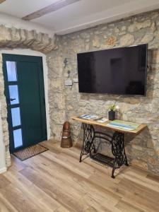 a stone wall with a table with a television on it at Apartman Mocic in Punat