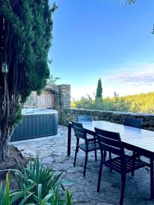 a patio with a wooden table and chairs at La maison Haut-perché townhouse with view and jacuzzi in Saumane-de-Vaucluse