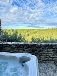 a bath tub sitting next to a stone wall at La maison Haut-perché townhouse with view and jacuzzi in Saumane-de-Vaucluse