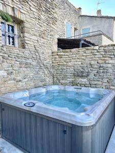 a hot tub in front of a stone building at La maison Haut-perché townhouse with view and jacuzzi in Saumane-de-Vaucluse