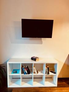 a white book shelf with a flat screen tv on top at Primiero Suite 3 downtown, garden in Transacqua