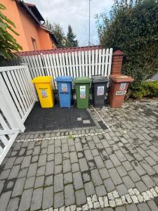 four trash cans lined up next to a white fence at Apartament Premium Pola in Bolesławiec