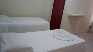 a white bed sitting next to a white wall at Hotel JB in São Mateus