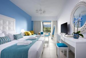 a hotel room with a bed and a mirror at Mythos Palace Resort & Spa in Georgioupolis