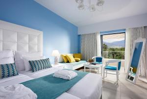 a bedroom with a bed and a room with a window at Mythos Palace Resort & Spa in Georgioupolis