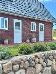 a brick house with white doors and a stone wall at Nije Haven Bed & Breakfast in Wrixum