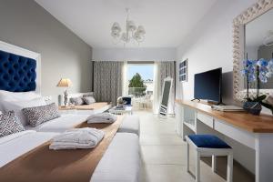 a bedroom with a bed and a desk with a television at Mythos Palace Resort & Spa in Georgioupolis