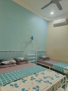 a bedroom with two beds and a ceiling fan at AZALEA Homestay Segamat in Segamat