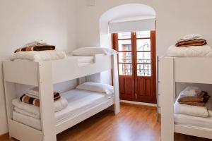 a room with white bunk beds and a door at Pórtico del Azahín in Cazalla de la Sierra