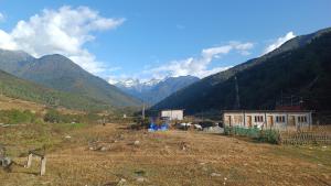 a field with a house and mountains in the background at Chug Ling Serene in Chug