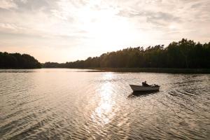 a man in a boat on a lake at Ferienhaus mit eigenem Boot & 2 Fahrrädern ca 100 m zum See An den Sieben Seen in Lohmen