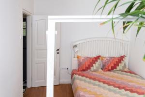 a white bedroom with a bed with a striped blanket at KIS CINKE Guesthouse in Tahitótfalu