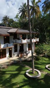 a house with a palm tree in front of it at Coco Drift Hostel Hiriketiya in Hiriketiya +23 photos