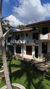 a house with a palm tree in front of it at Coco Drift Hostel Hiriketiya in Hiriketiya
