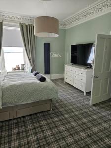 a bedroom with a bed and a flat screen tv at The Old Bank bed & breakfast in Millport