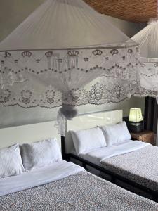 two beds sitting next to each other in a bedroom at Palm Garden Resort in Gisenyi