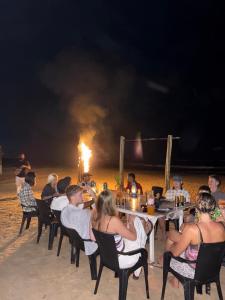 a group of people sitting at a table on the beach at Coco Drift Hostel Hiriketiya in Hiriketiya
