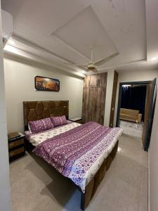 a bedroom with a large bed with a purple comforter at Two Bed Appartment in Islamabad