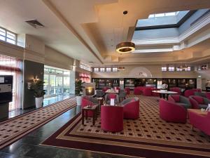 a restaurant with pink chairs and tables in a lobby at Orida Maidstone in Maidstone
