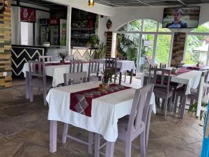 a dining room with white tables and chairs in a restaurant at Palm Garden Resort in Gisenyi