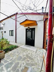 a house with a black door and a stone patio at Davit batoni Apartment in Mtskheta in Mtskheta