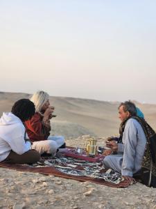 a group of people sitting on a blanket on the beach at Ancient Bakyard Guesthouse in Abū Şīr