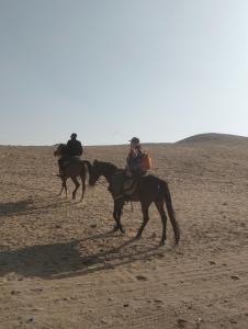 two people riding horses in the desert at Ancient Bakyard Guesthouse in Abū Şīr