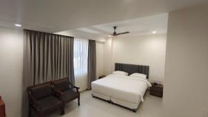 a bedroom with a white bed and a chair at Darling Grand SME in Vellore +7 photos