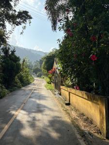 an empty road with a fence and flowers at Hornbills Garden in Khlaung Phai Bae