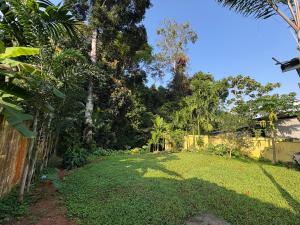 a yard with a fence and trees and grass at Hornbills Garden in Khlaung Phai Bae