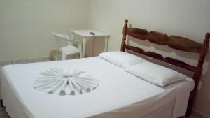 a bedroom with a white bed with a wooden headboard at Hotel JB in São Mateus