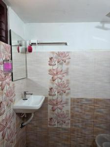 a bathroom with a sink and pink flowers on the wall at Ostello in Varkala
