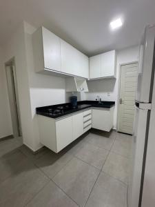 a kitchen with white cabinets and a black counter top at Studio perfeito para trabalho, concurso ou compras in João Pessoa