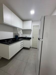 a kitchen with white cabinets and a stainless steel refrigerator at Studio perfeito para trabalho, concurso ou compras in João Pessoa