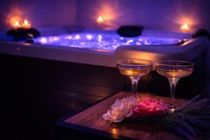 two glasses of wine on a table next to a bath tub at fuga romantica in Benisuera