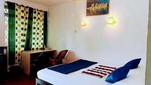 a bedroom with a bed and a table and a chair at JBL Guest House , Arombal , Goa in Arambol