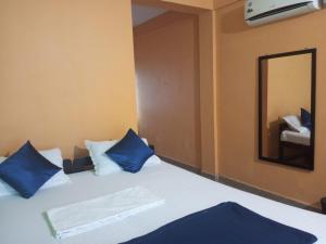 a bedroom with a bed with blue pillows and a mirror at JBL Guest House , Arombal , Goa in Arambol