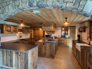a large kitchen with wooden cabinets and a stone wall at Les Chryolles -Les Petits loups in Valmeinier