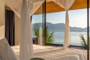 a bedroom with a bed with a view of the water at The Cozy Beachfront Phuket in Patong Beach