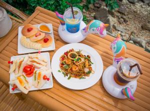 a table with plates of food and drinks on it at The Cozy Beachfront Phuket in Patong Beach +69 photos