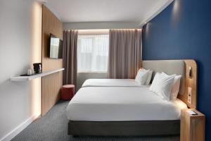 a hotel room with a large bed and a blue wall at Holiday Inn Express Antwerpen City North by IHG in Antwerp