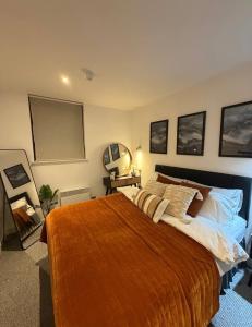 a bedroom with a large bed with a orange blanket at Advent House Ancoats Hosted Apartment in Manchester