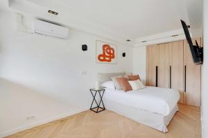 a white bedroom with a bed and a tv at Charming Apt with AC & balcony in Suresnes