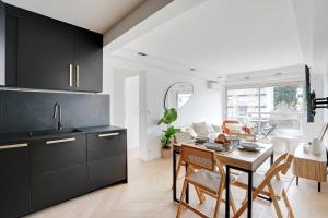 a kitchen with black cabinets and a table with chairs at Charming Apt with AC & balcony in Suresnes