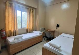 a bedroom with two beds and a window and a desk at JL Suites by Hiverooms in Cebu City