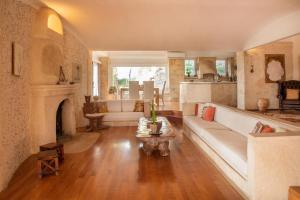 a living room with a white couch and a fireplace at Majestique Villa Aegina in Egina