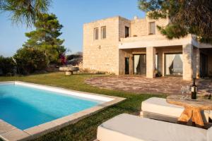 a villa with a swimming pool in front of a house at Majestique Villa Aegina in Egina